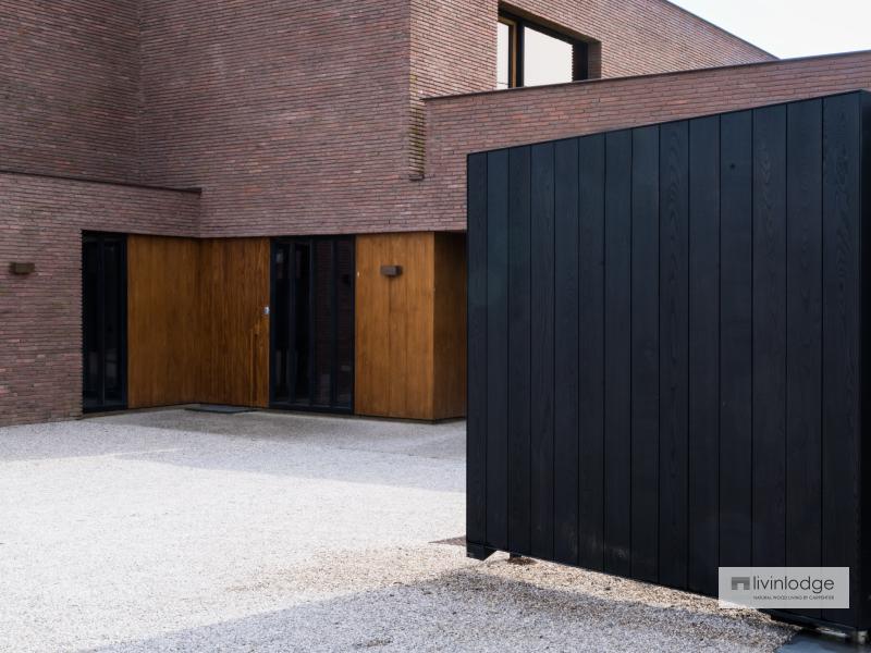 Portail en bois noir s'intégrant parfaitement à une villa moderne aux lignes épurées